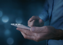 Mann tippt auf Smartphone in Supermarkt